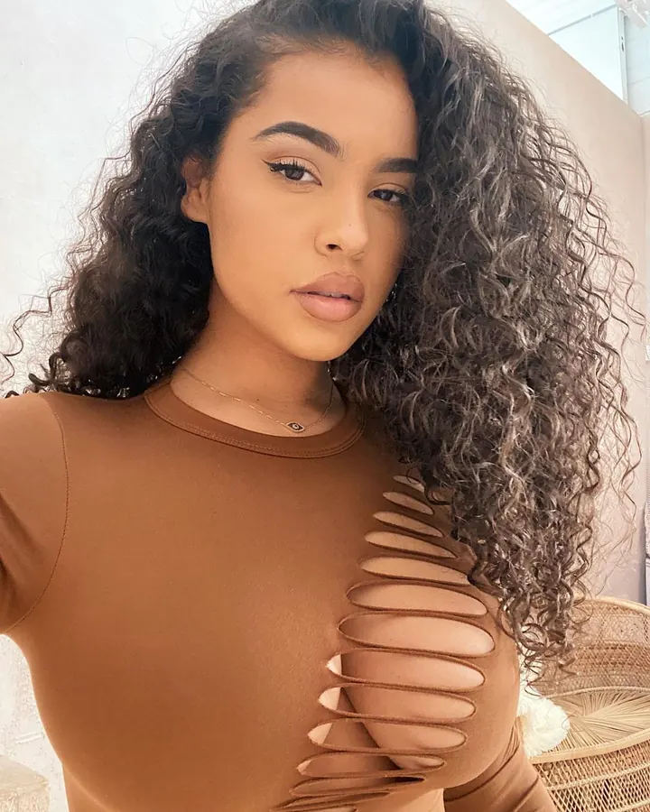 Femme en tenue marron avec découpes, regard intense