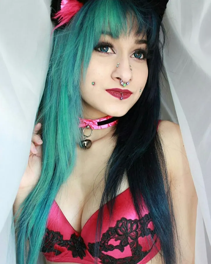 Femme aux cheveux bruns-noirs et yeux verts, en sous-vêtements roses, vue de dos, penchée en avant.
