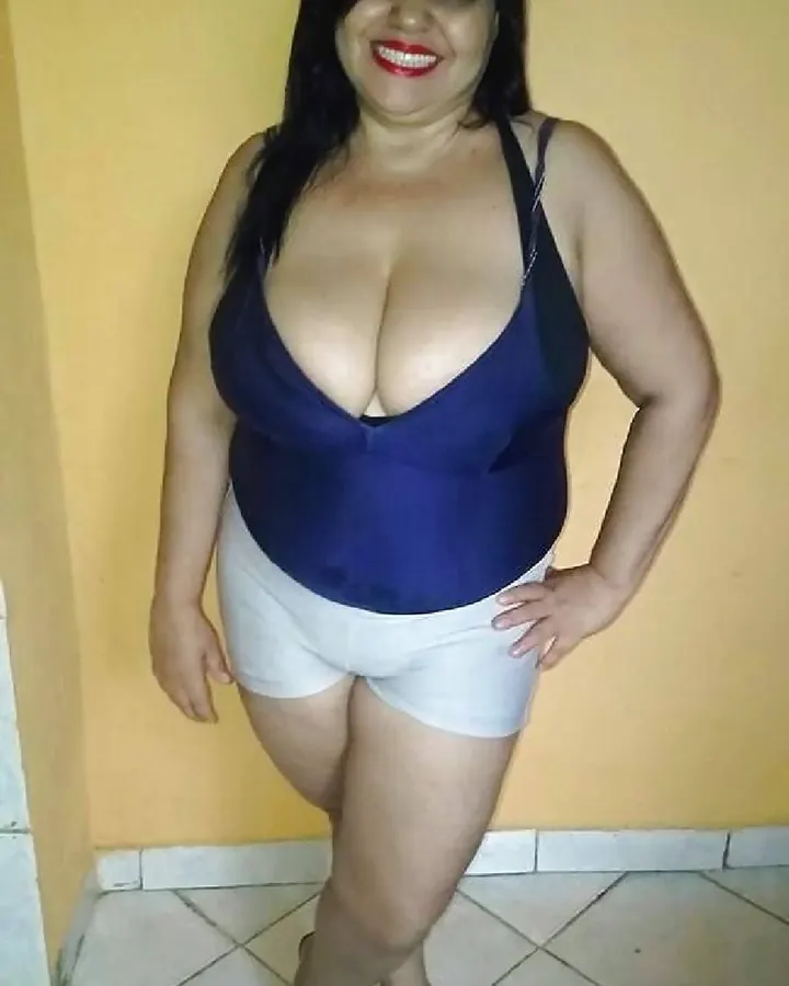Femme en haut bleu foncé et shorts blancs, souriant à l'appareil.