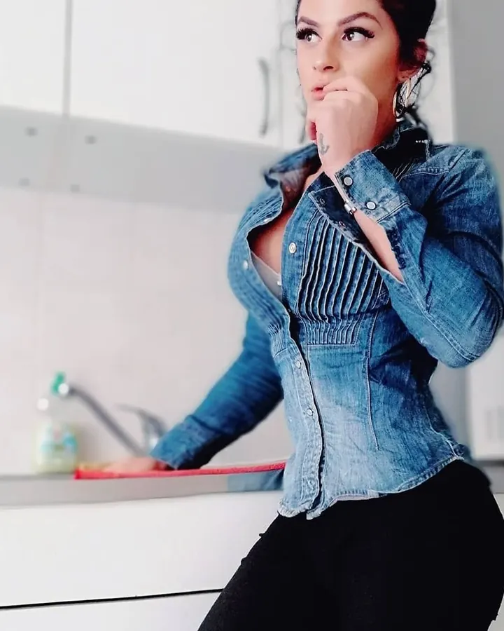 Femme arabe de 25 à 35 ans en tenue de Noël rouge, posant de dos devant une grande fenêtre avec vue sur une ville.